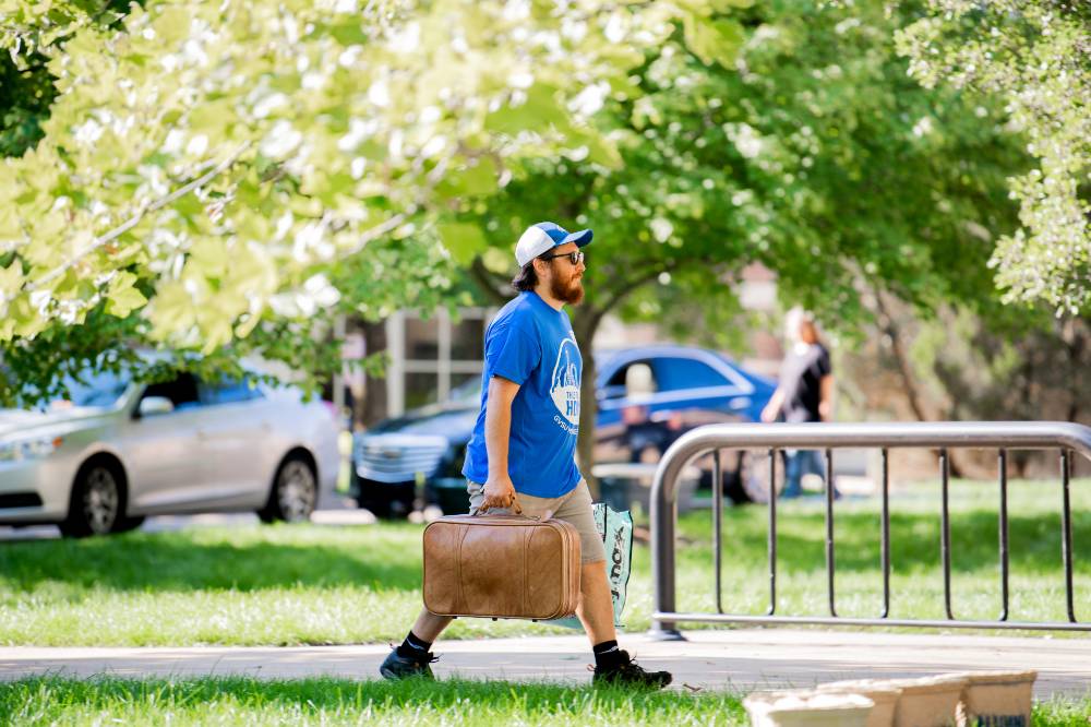 An Alumnus carrying a student's suitcase.